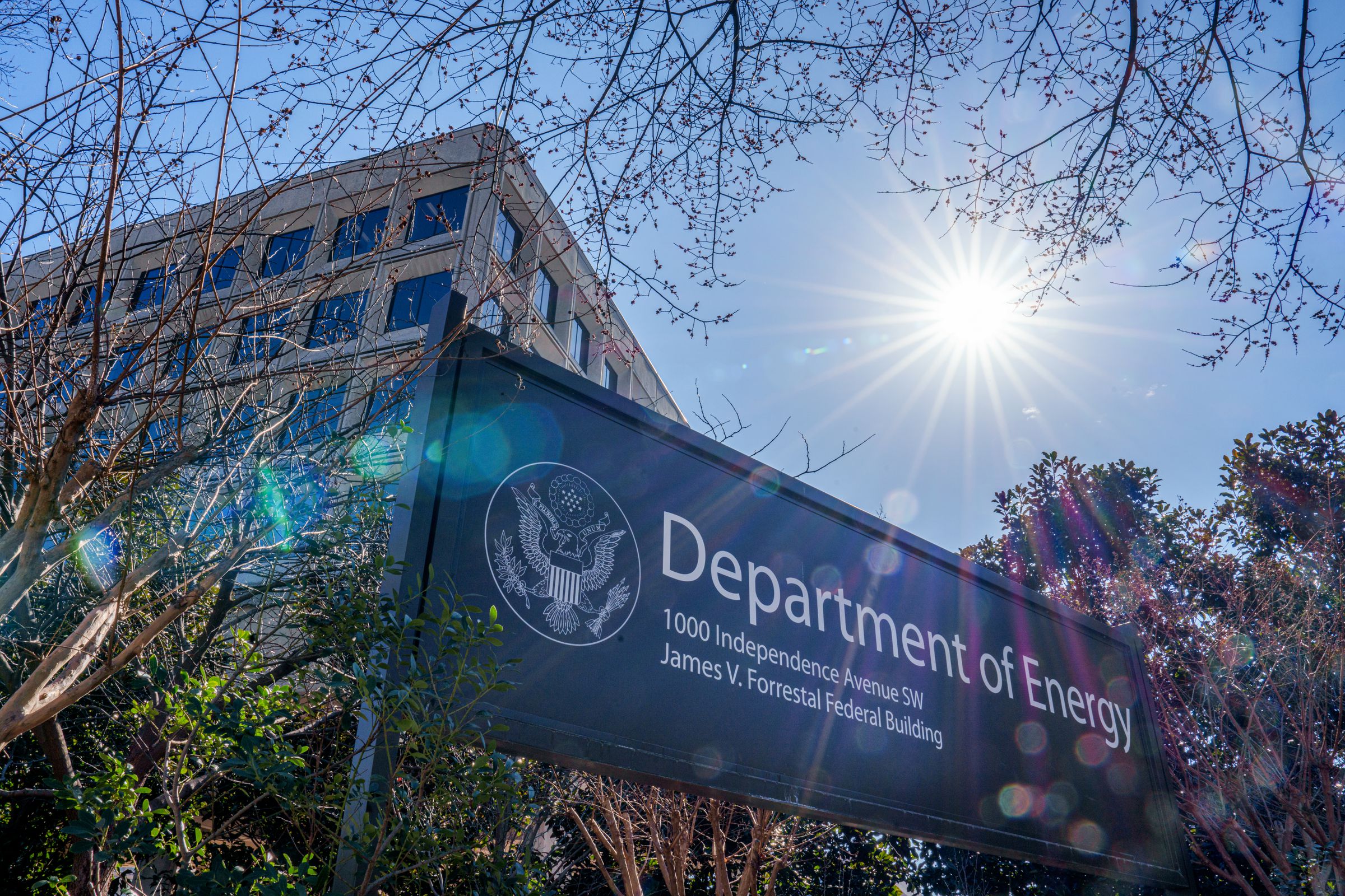 The sun flares over the sign marking the location of the US Department of Energy headquarters building