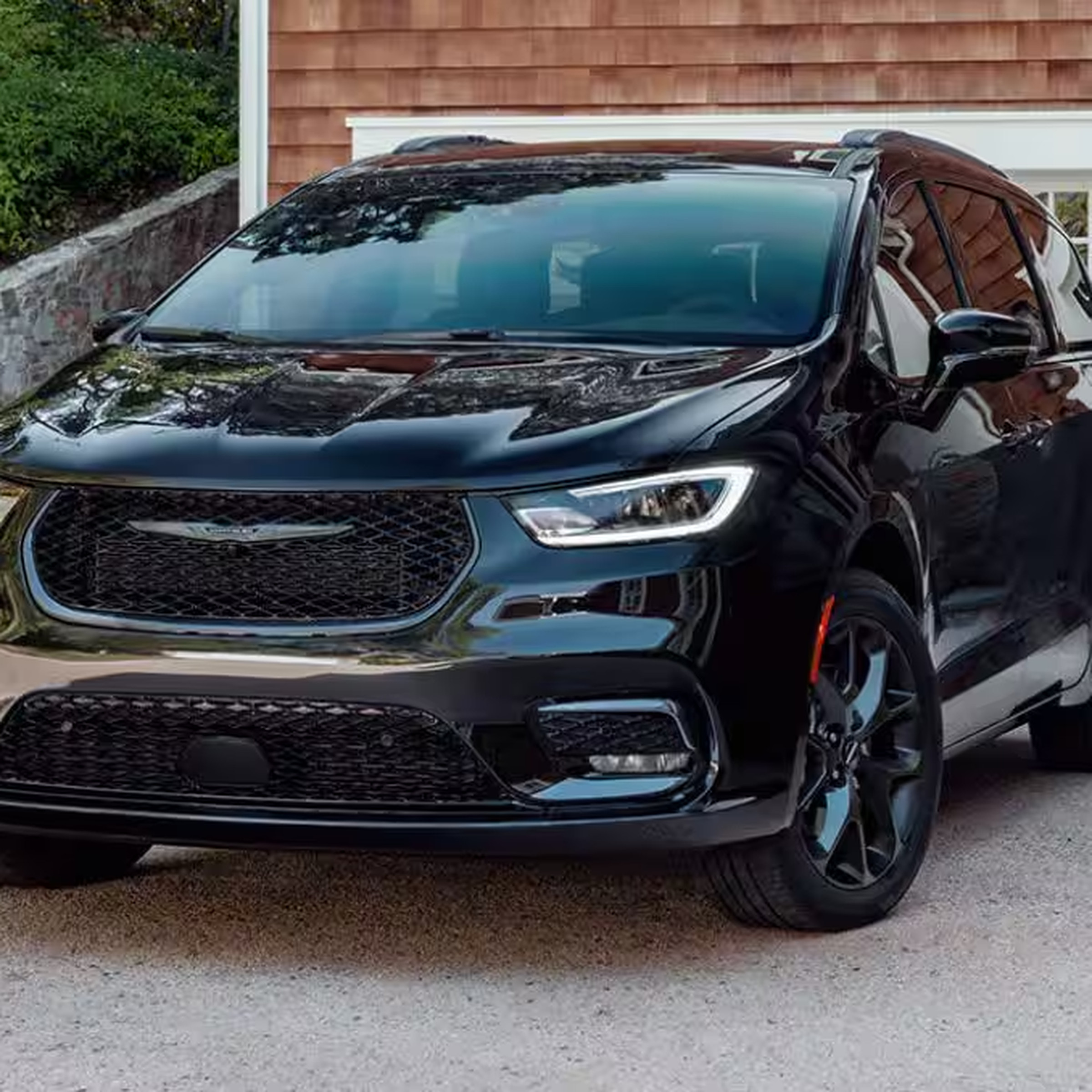 A 2024 Chrysler Pacifica in dark blue, sitting in a driveway. Three-quarter view of the vehicle, taken from the front.