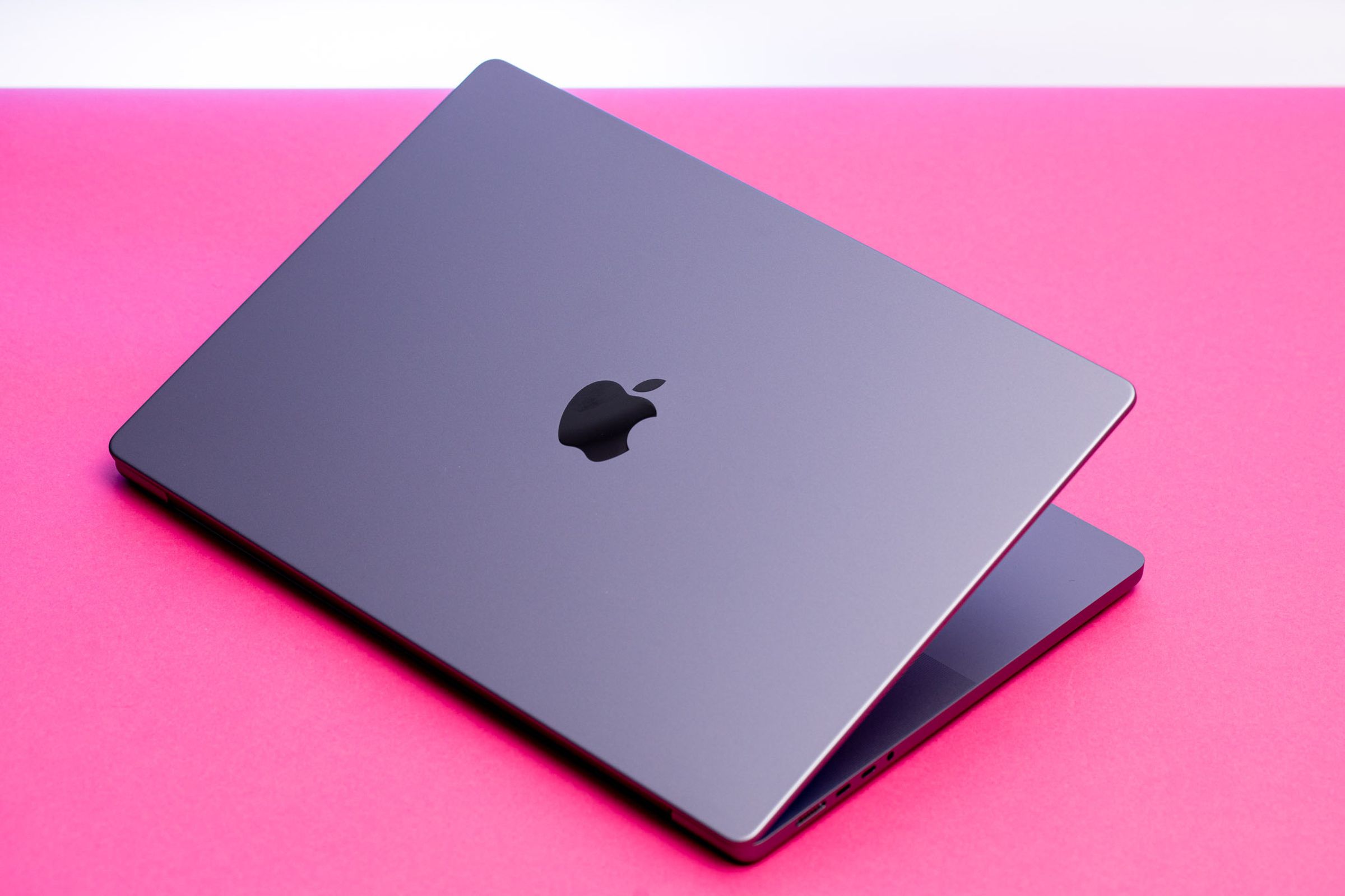 A photo showing a MacBook on a pink background