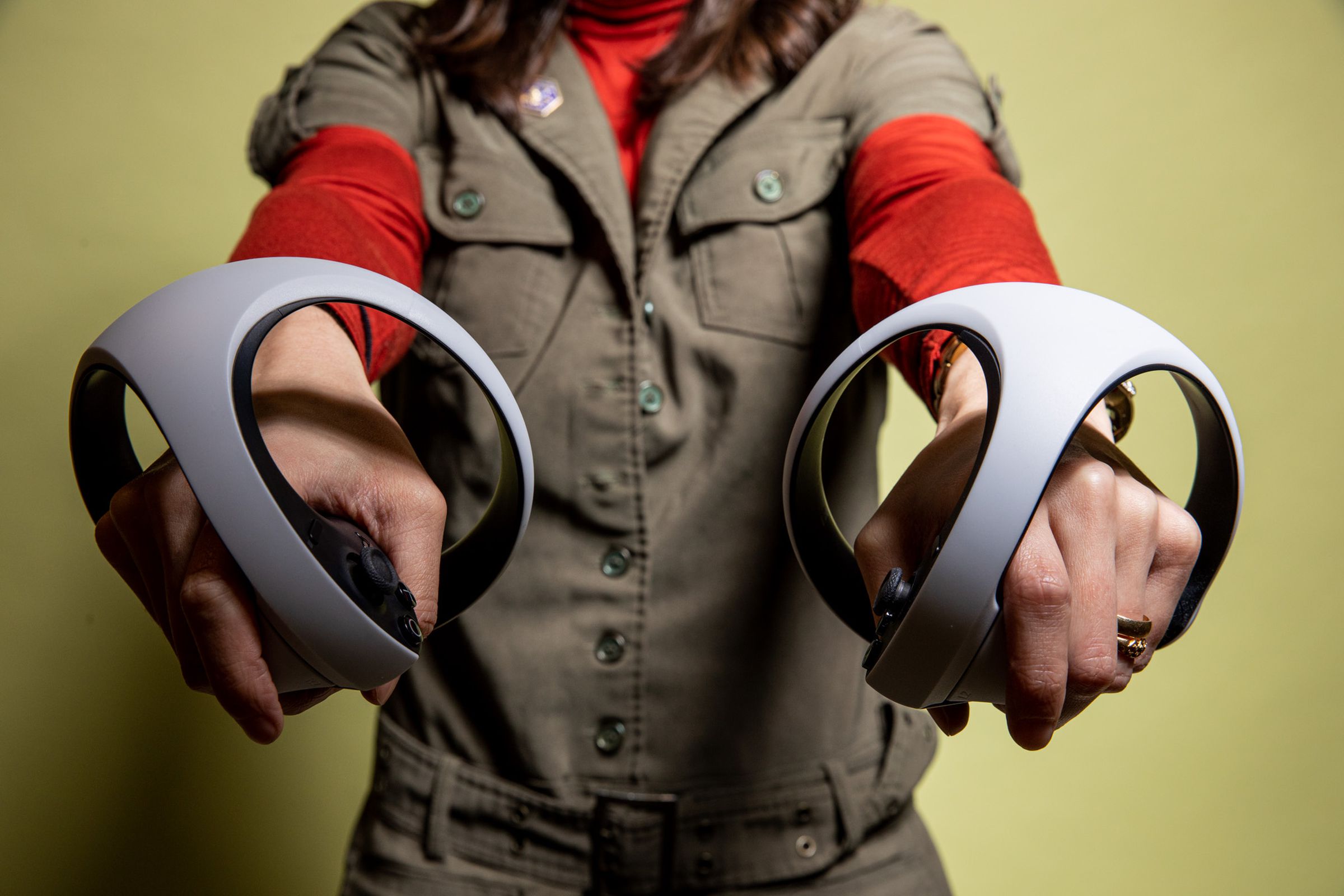 Adi holds both controllers out directly in front of her, towards the camera.