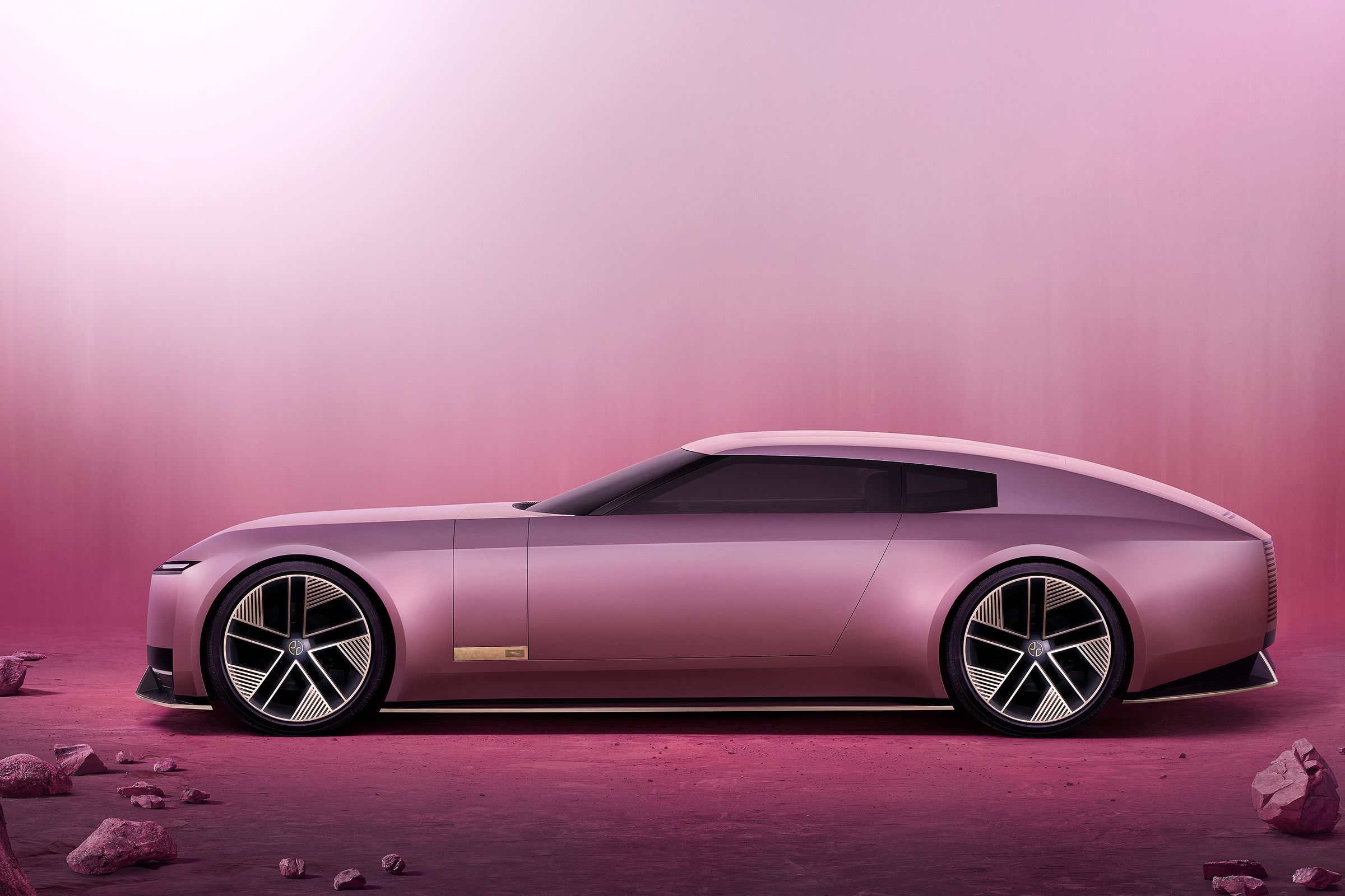 Jaguar Type 00 in pink, seen from the side on a pink background with stones surrounding the sleek two-door coupe.