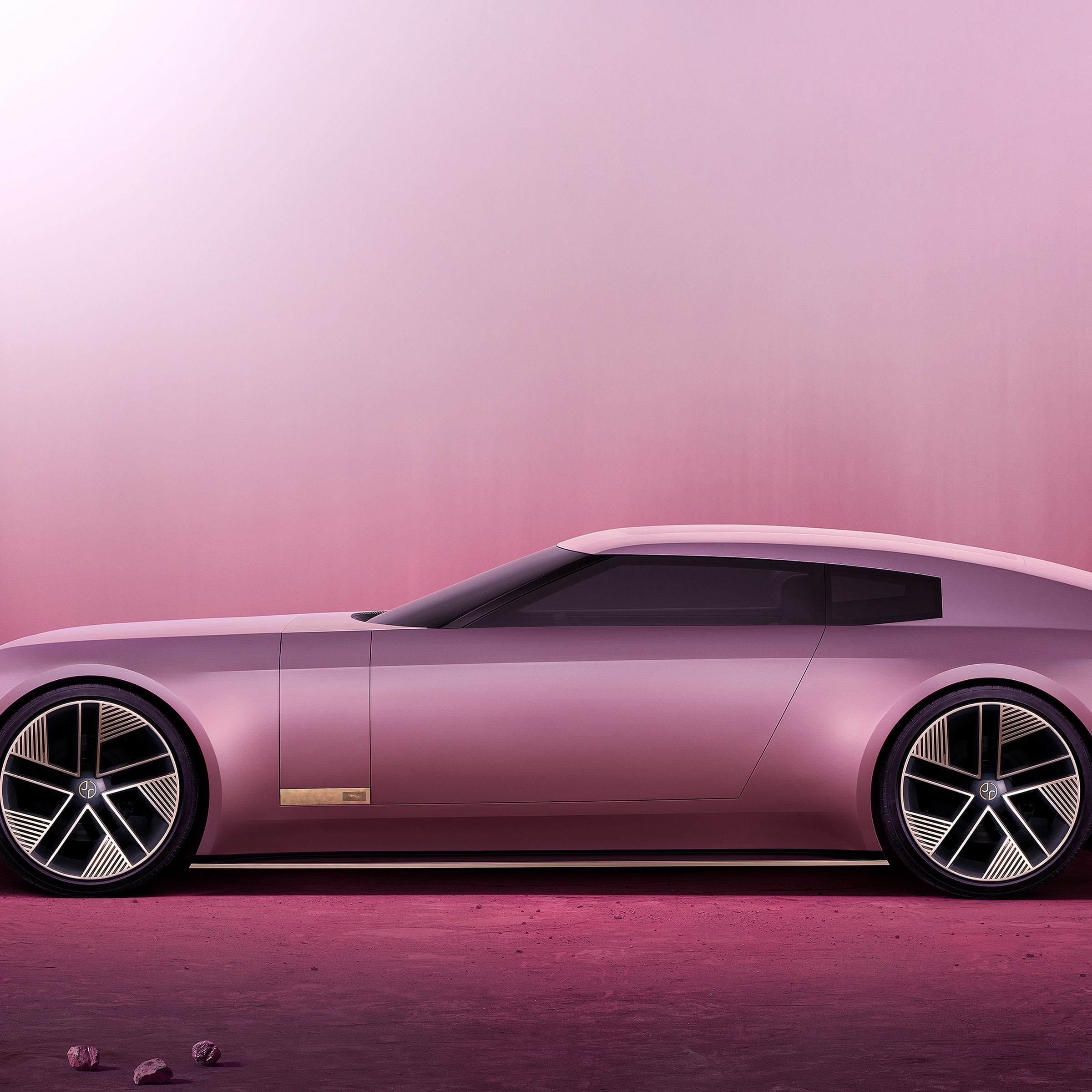 Jaguar Type 00 in pink, seen from the side on a pink background with stones surrounding the sleek two-door coupe.