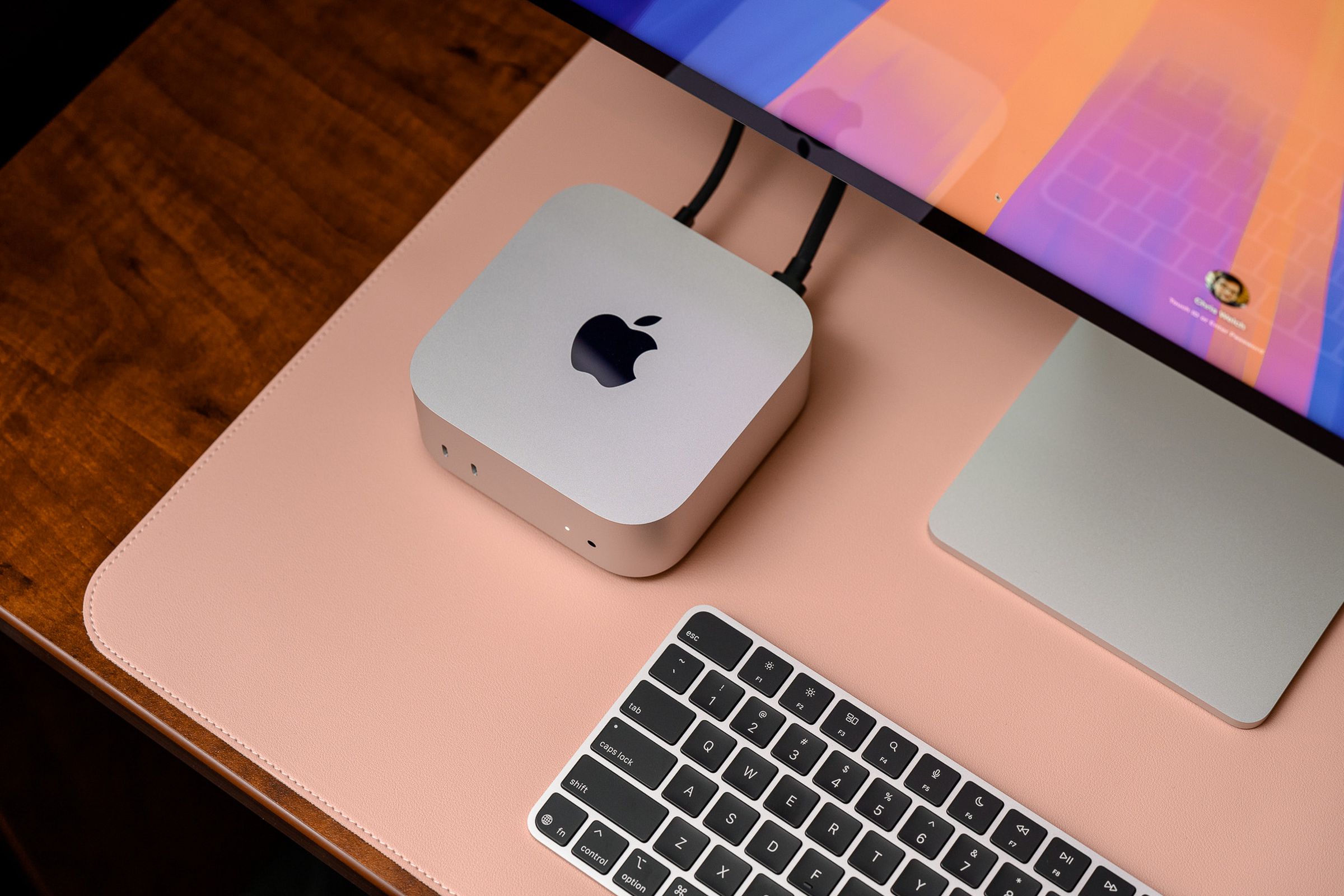 A hands-on photo of Apple’s 2024 Mac Mini on a desk beside a keyboard and Studio Display.