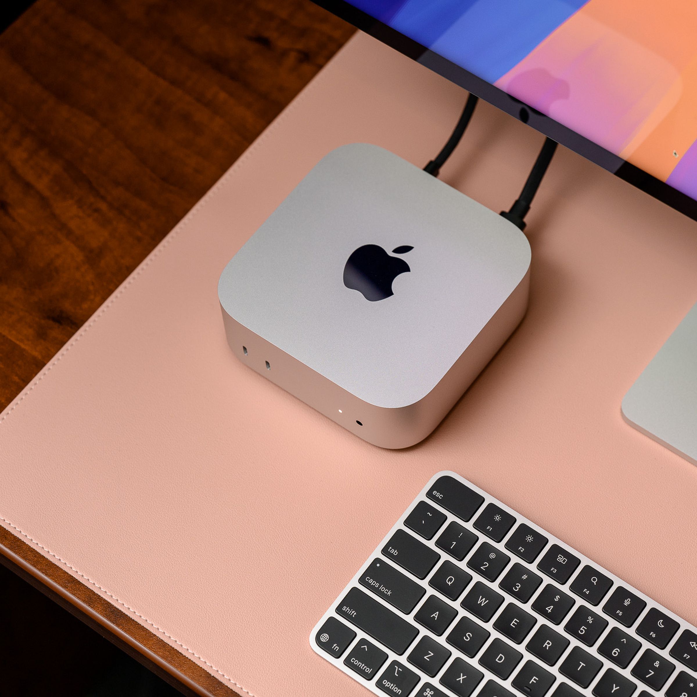 A hands-on photo of Apple’s 2024 Mac Mini on a desk beside a keyboard and Studio Display.