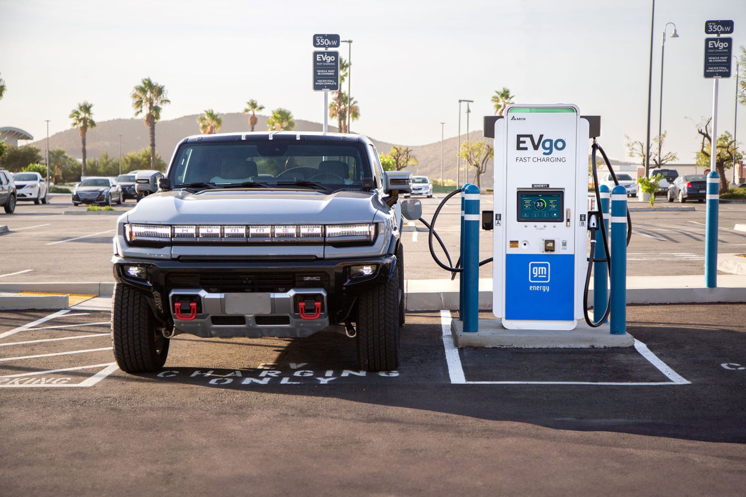 Picture of an EV truck in a parking lot, plugged into an EVgo / GM Energy fast charger.