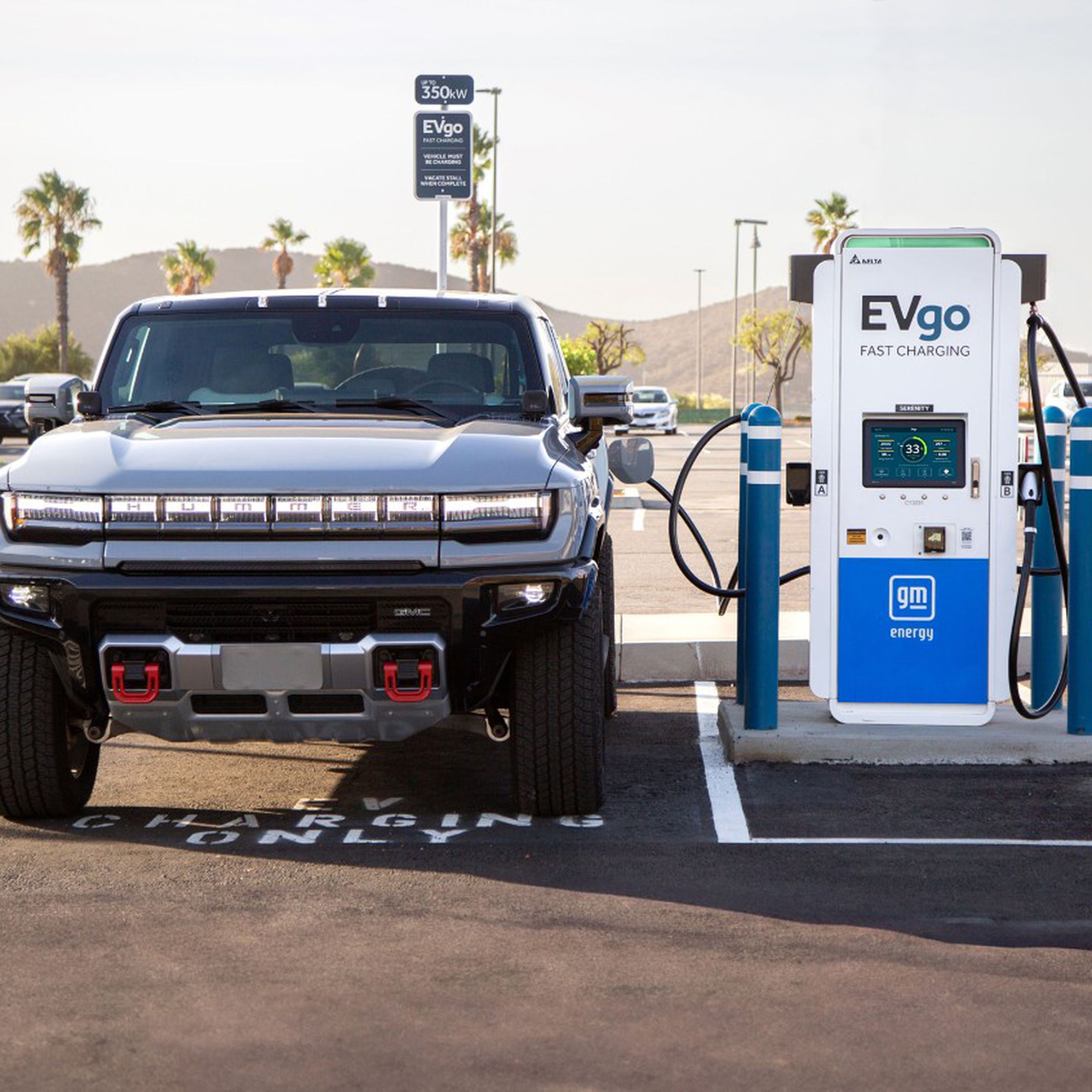 Picture of an EV truck in a parking lot, plugged into an EVgo / GM Energy fast charger.