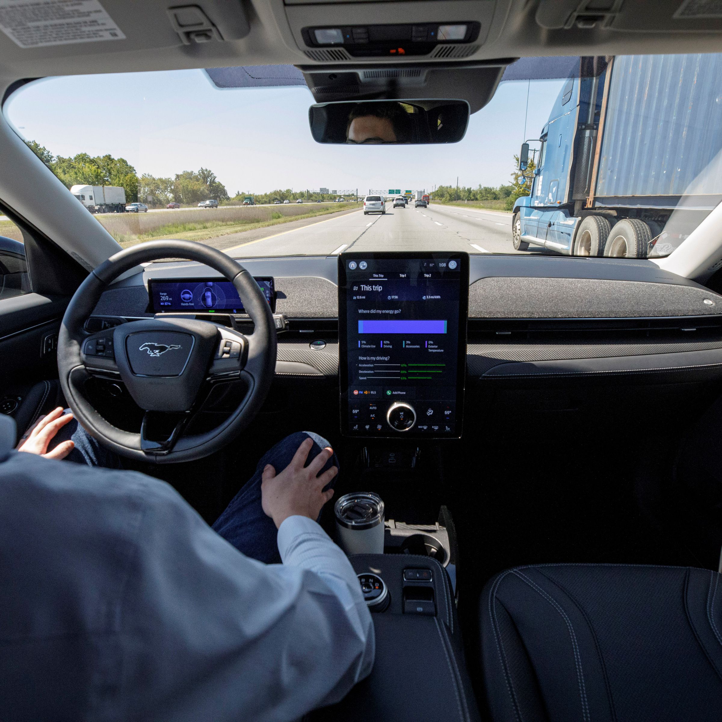 A back seat view of a man behind the wheel of a Ford Mustang on the highway