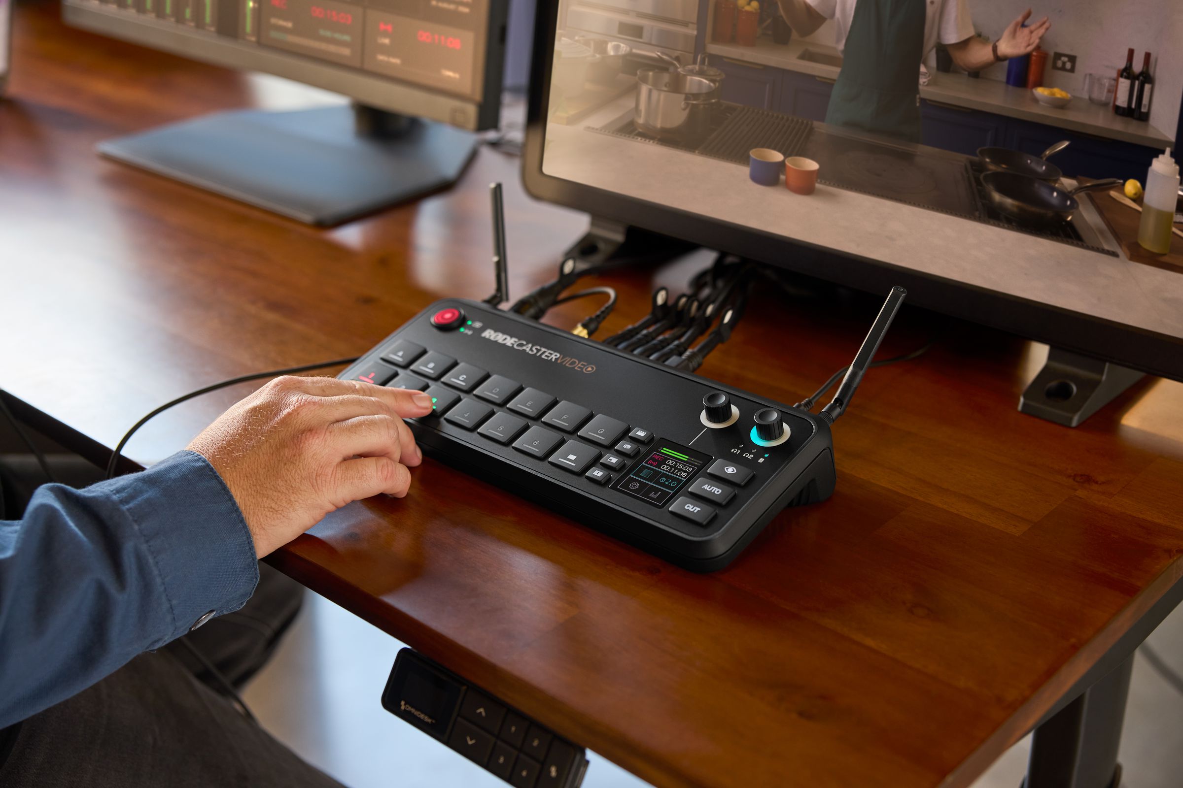 The Rodecaster Video on a table, a person pressing on of the buttons.